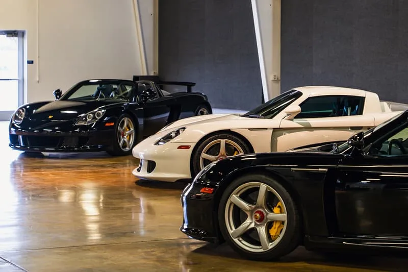 Trois voitures de sport noires et blanches exposées dans un garage.