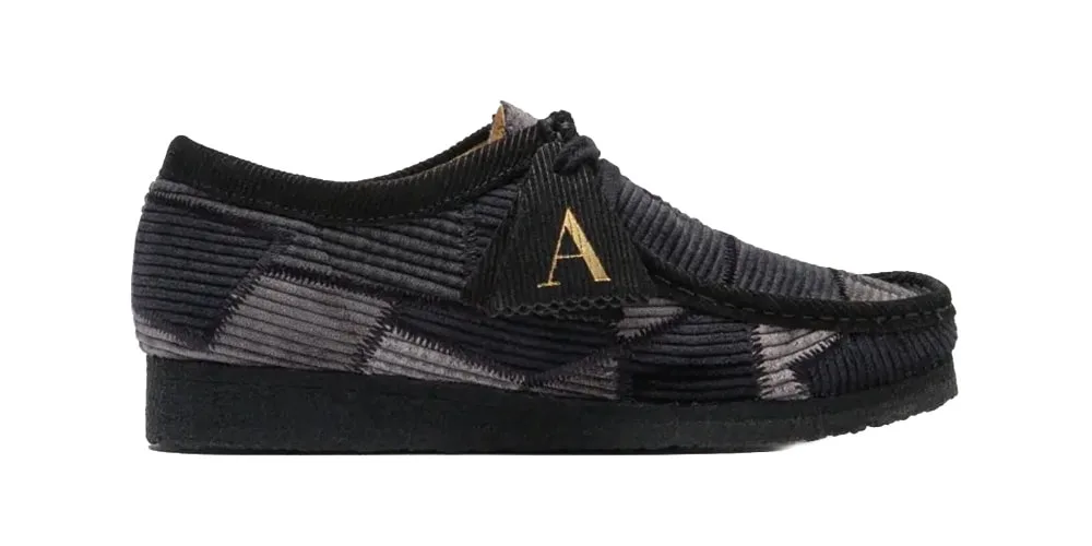 Chaussure en velours côtelé noir avec lettre dorée 'A'.