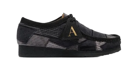 Chaussure en velours côtelé noir avec lettre dorée 'A'.