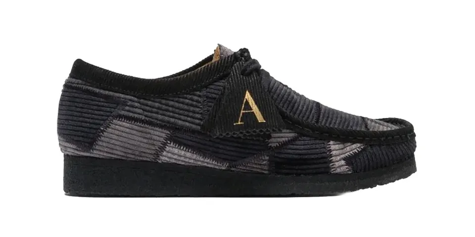 Chaussure en velours côtelé noir avec lettre dorée 'A'.
