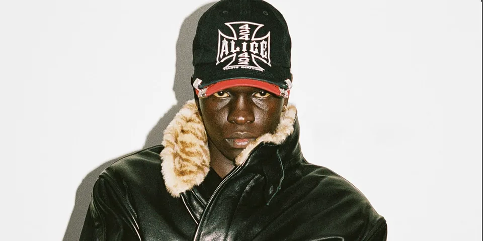 Homme avec casquette et veste en cuir avec col en fourrure.