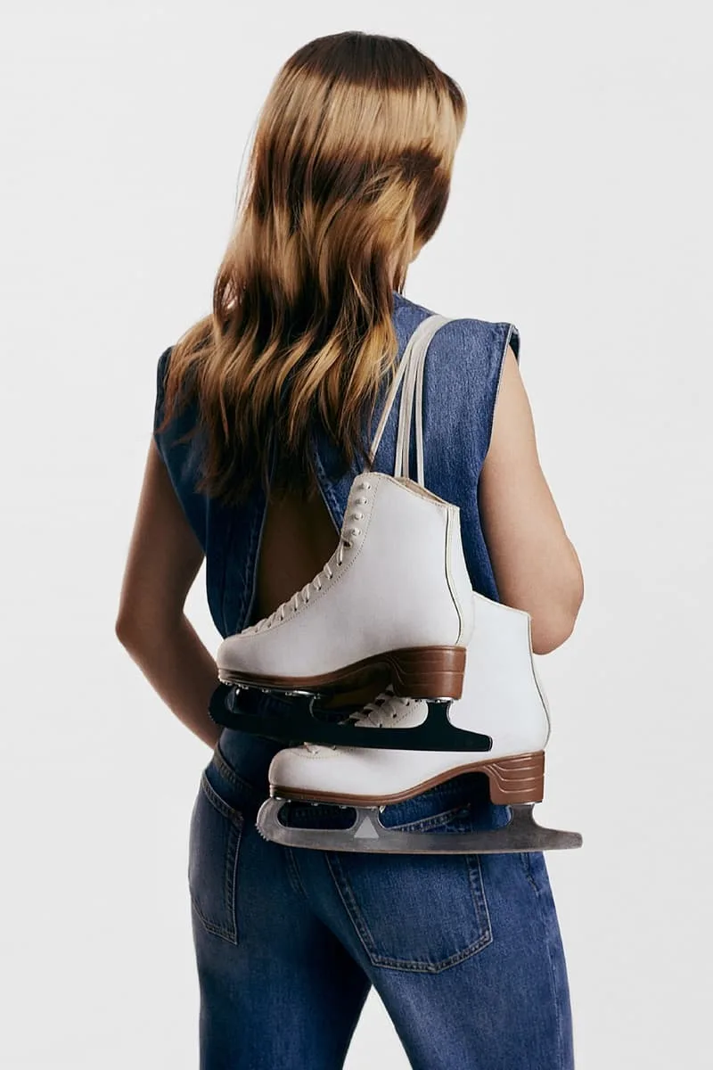 Femme en jean portant des patins à glace sur l'épaule
