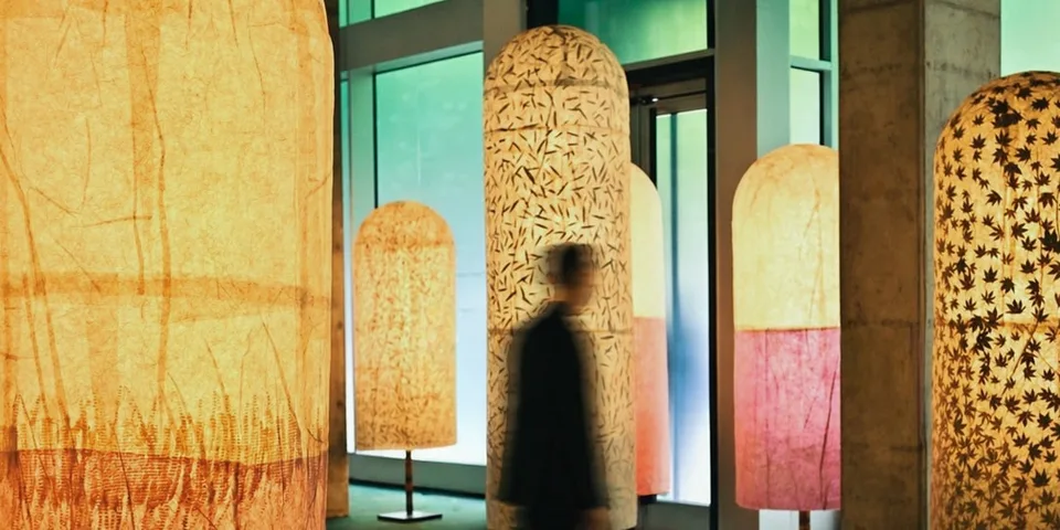 Personne floue passant devant des grandes lampes artistiques dans un hall.