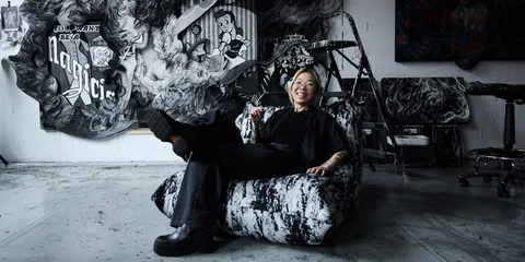 Personne assise dans un studio artistique avec des œuvres en arrière-plan.