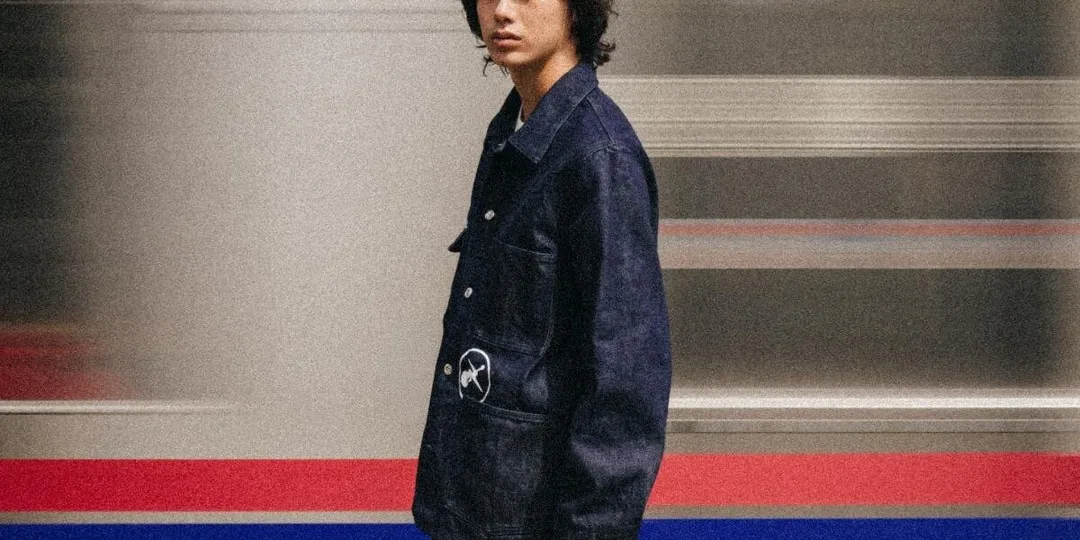 Personne en veste en jean devant un fond flou de train.