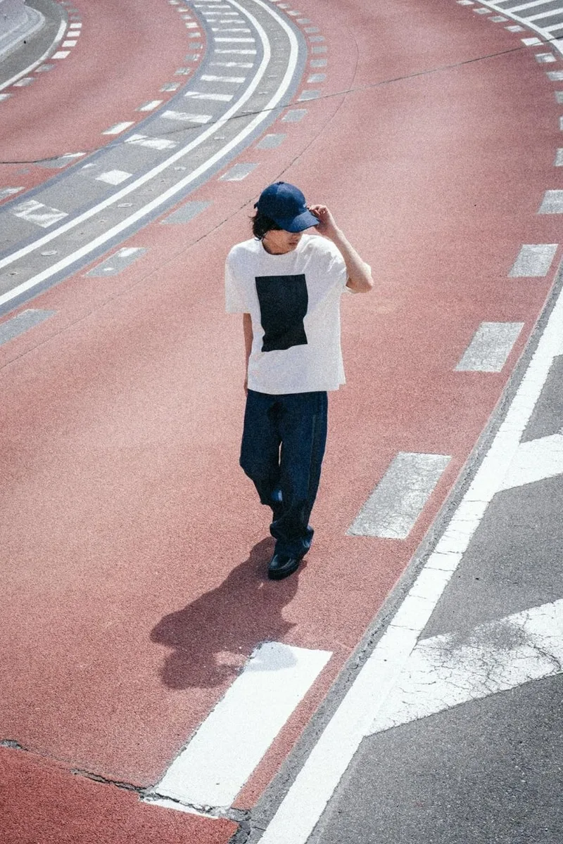 Personne marchant sur une route avec un t-shirt blanc et un pantalon bleu.