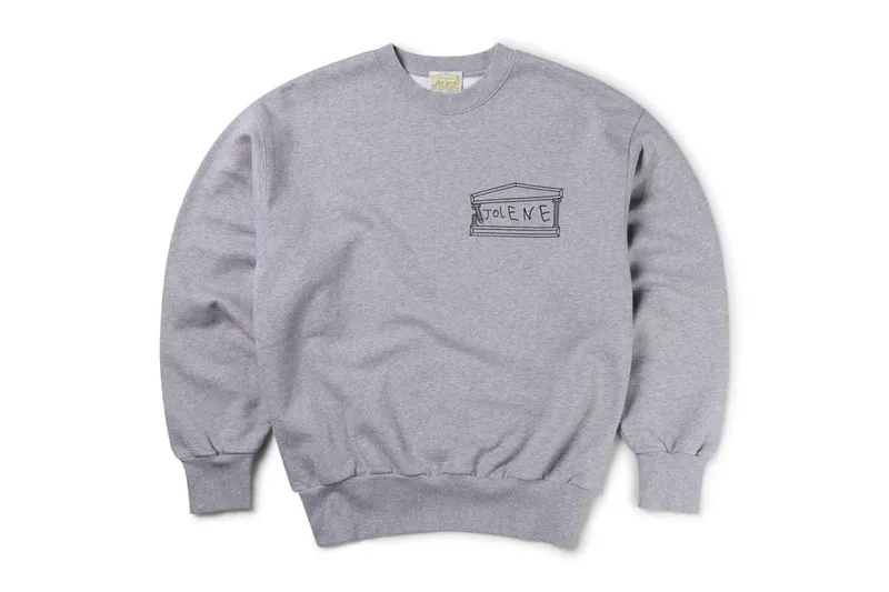 Sweat-shirt gris avec dessin de bâtiment et texte indéchiffrable.