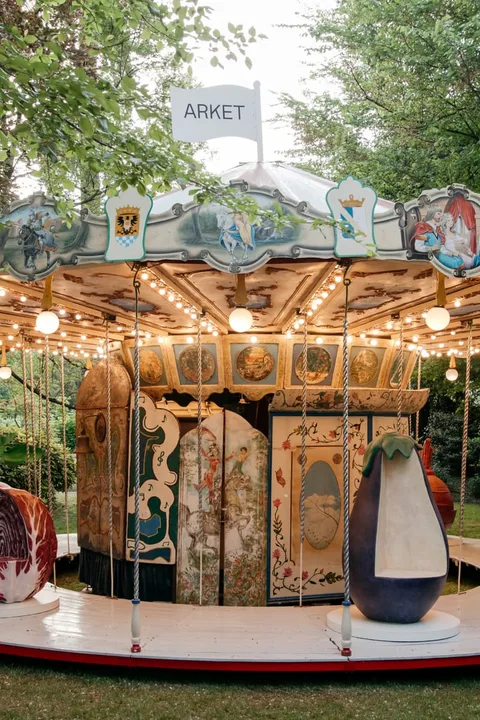 Carrousel vintage dans un jardin avec enseigne ARKET.