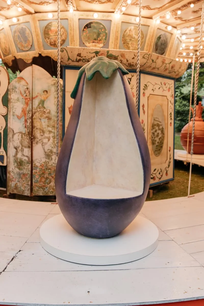 Manège avec siège en forme d'aubergine, fond décoratif.