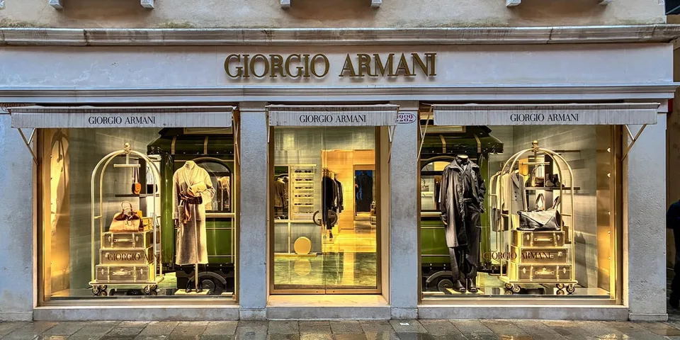 Vitrine Giorgio Armani avec mannequins et vêtements, éclairage doré.