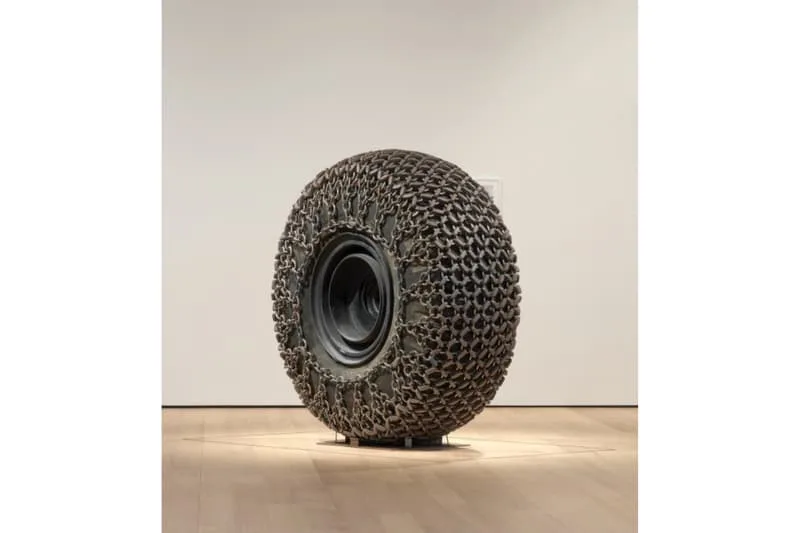 Sculpture en pneu avec texture unique exposée sur un socle en galerie d'art.