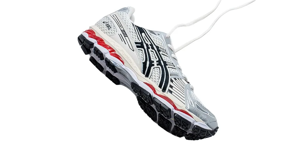 Chaussure de sport blanche, noire et rouge avec semelle texturée.