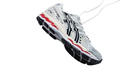 Chaussure de sport blanche, noire et rouge avec semelle texturée.