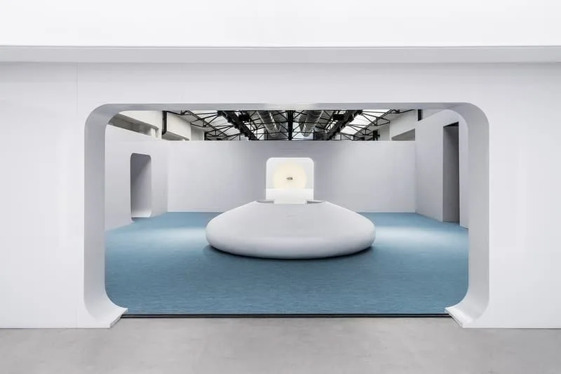 Salle moderne avec sculpture centrale et lumière blanche.
