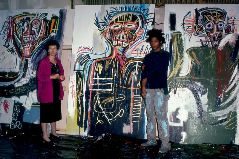Femme et homme devant des peintures abstraites colorées dans un atelier.