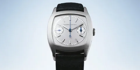 Montre en acier avec cadran argenté et aiguilles bleues.