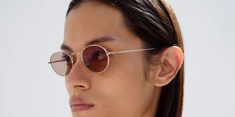Personne portant des lunettes rondes avec des verres teintés.
