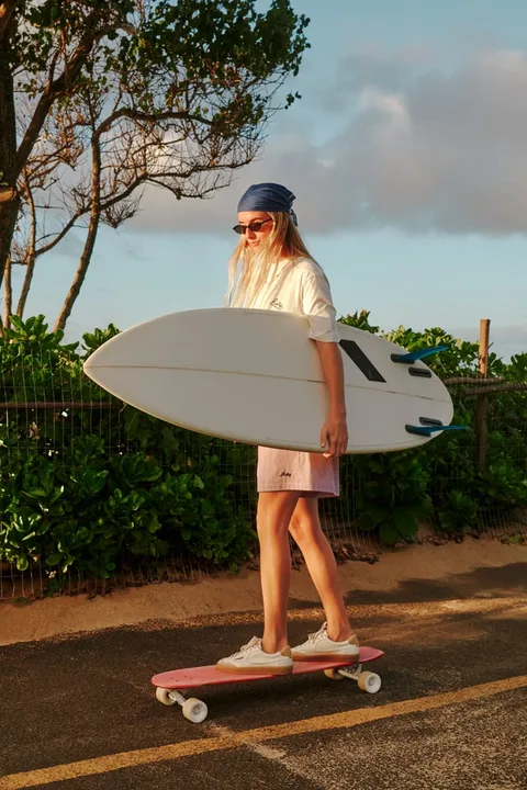 Personne skate avec une planche de surf sur un chemin ensoleillé.