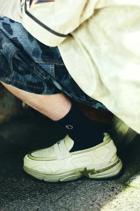 Homme avec baskets beiges et chaussettes noires, style urbain décontracté.