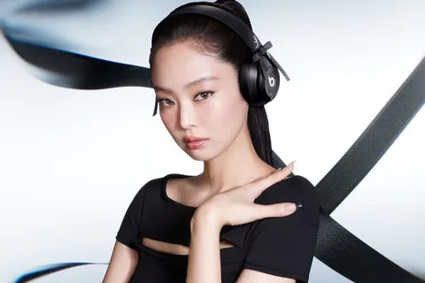 Personne posant avec un casque audio noir, fond abstrait.