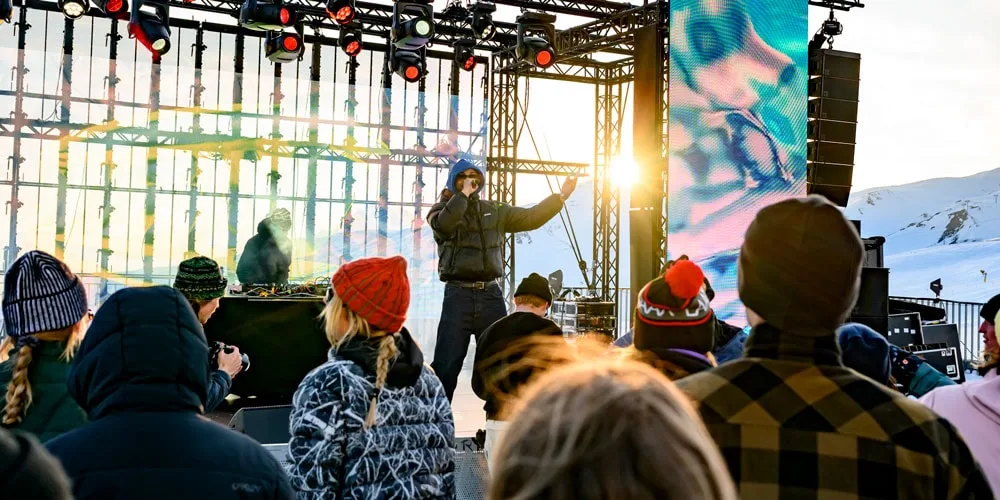 Concert en plein air avec un chanteur sur scène, public vêtu chaudement.