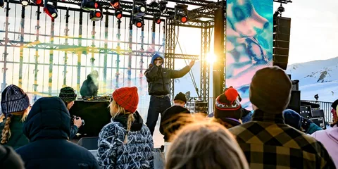Concert en plein air avec un chanteur sur scène, public vêtu chaudement.