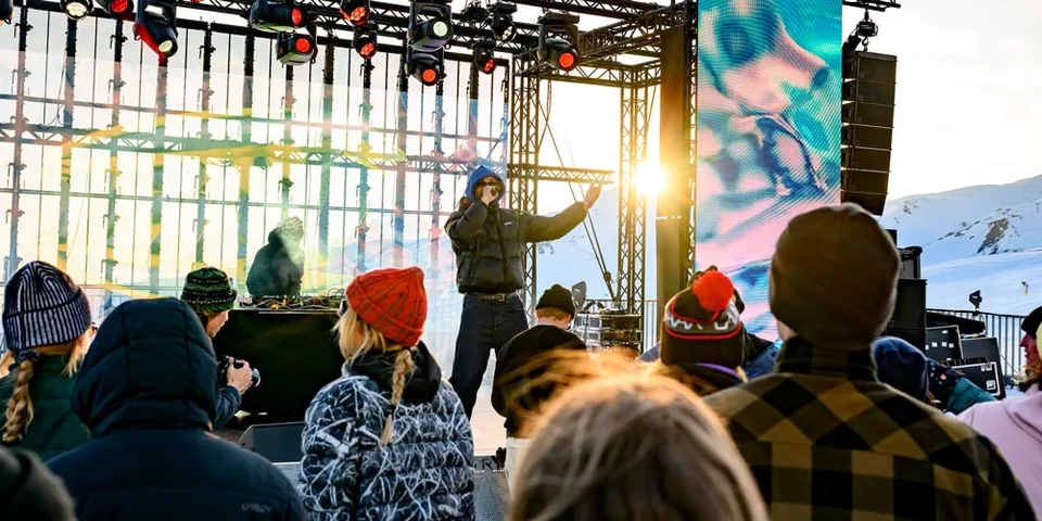 Concert en plein air avec un chanteur sur scène, public vêtu chaudement.
