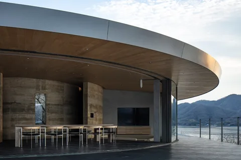 Bâtiment moderne avec intérieur en bois et vue sur les montagnes et l'eau.