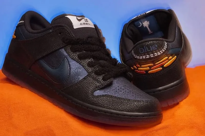 Chaussures noires avec détails bleus et orange, sur fond bleu et orange.