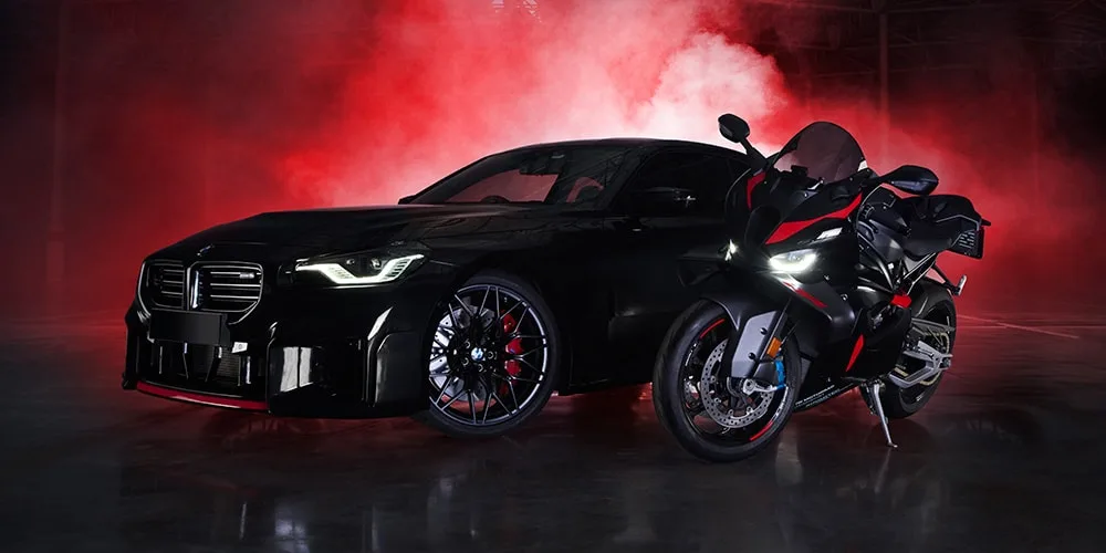 Voiture noire et moto avec fumée rouge en arrière-plan.