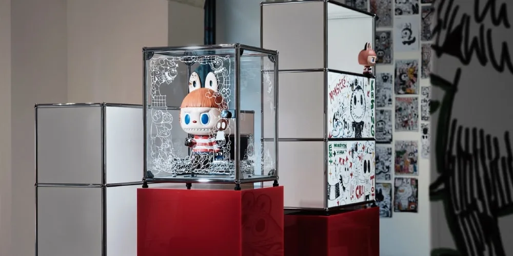 Exposition de jouets avec figurines dans des cubes en verre et art mural en arrière-plan.