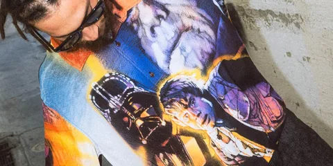 Homme avec chemise graphique de Star Wars, lunettes de soleil noires et dreadlocks