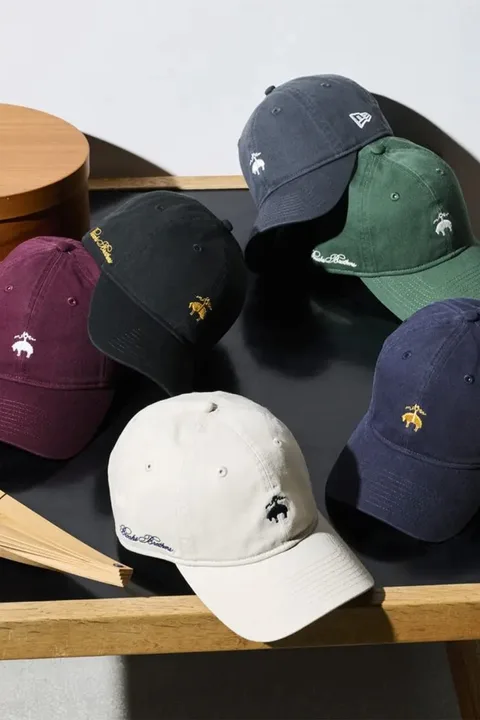Cinq casquettes de différentes couleurs sur une surface en bois.