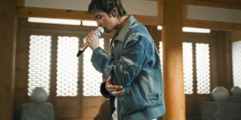 Chanteur avec micro dans une pièce en bois traditionnel.