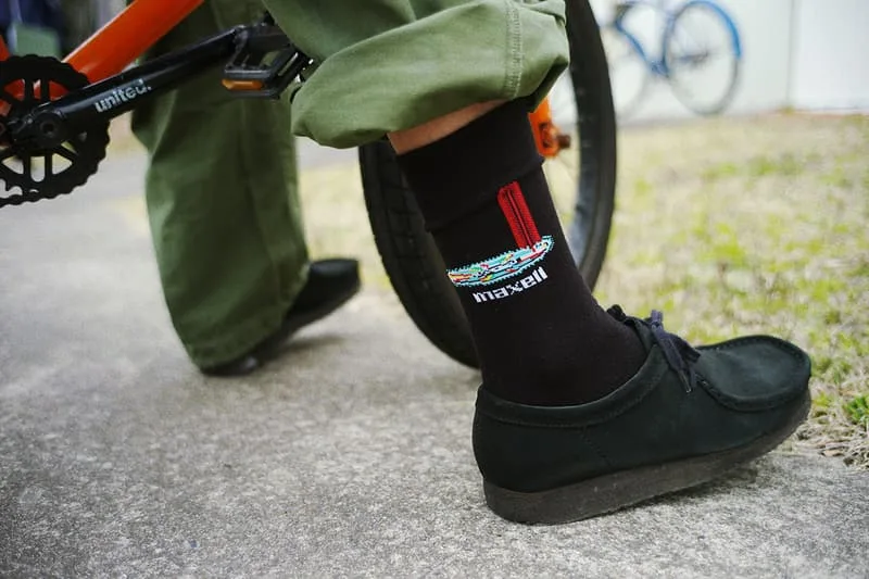 Cycliste avec chaussettes noires et vélo orange, chaussure noire.