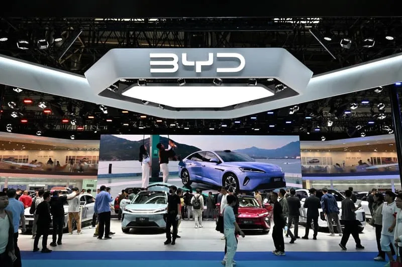 Exposition automobile avec le logo BYD et des voitures exposées.