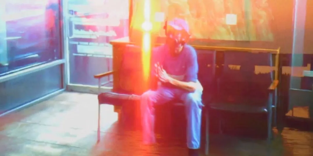 Homme assis dans un endroit illuminé et coloré, ambiance floue et lumineuse.