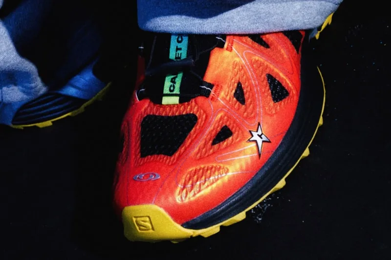 Chaussure de sport orange et jaune avec étoile noire et texte vert.