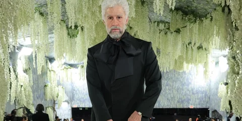 Homme en noir avec décor floral suspendu.