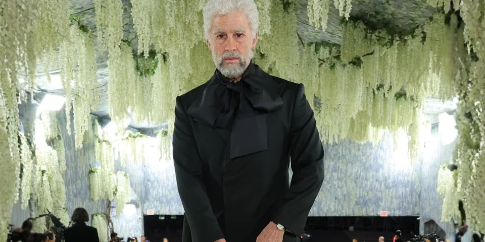 Homme en noir avec décor floral suspendu.