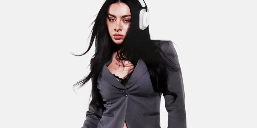 Femme en blazer gris avec casque audio blanc.