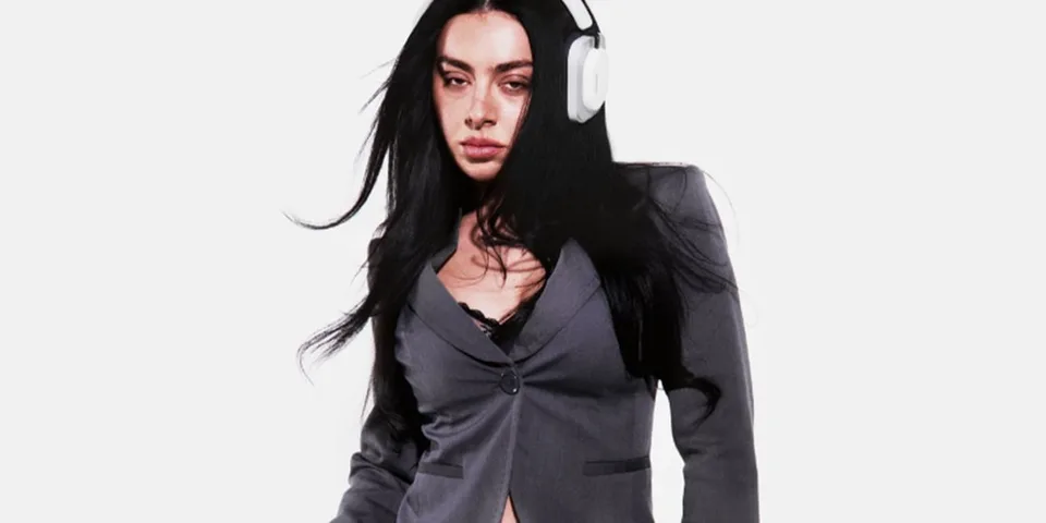 Femme en blazer gris avec casque audio blanc.