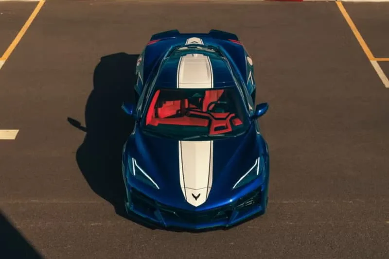 Voiture de sport bleue avec intérieur rouge, vue de dessus, sur un parking.