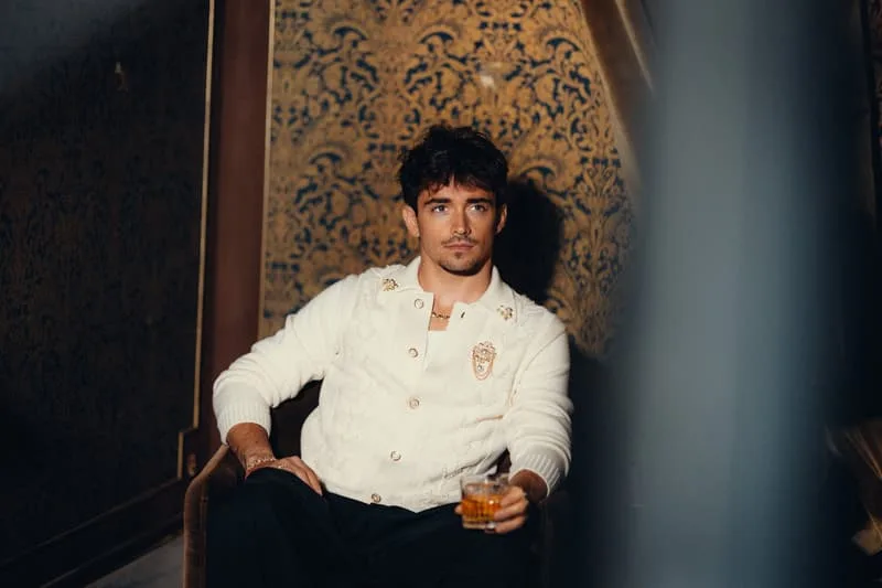 Homme assis avec un verre à la main, fond doré.