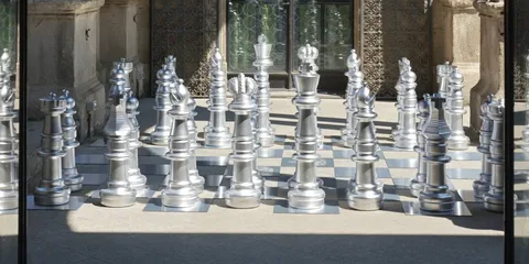 Échiquier géant avec pièces argentées sur échiquier extérieur.