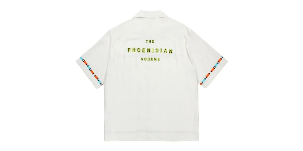 Chemise blanche avec texte jaune "The Phoenician Scheme".