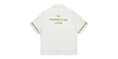Chemise blanche avec texte jaune "The Phoenician Scheme".