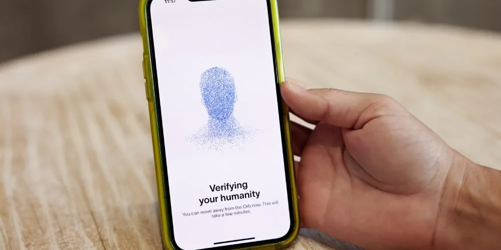 Personne tenant un téléphone, écran affichant 'Vérification de votre humanité'.