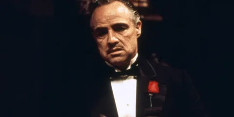 Homme en smoking avec une rose rouge à la boutonnière.