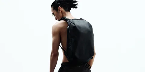 Personne portant un sac à dos noir moderne et minimaliste.